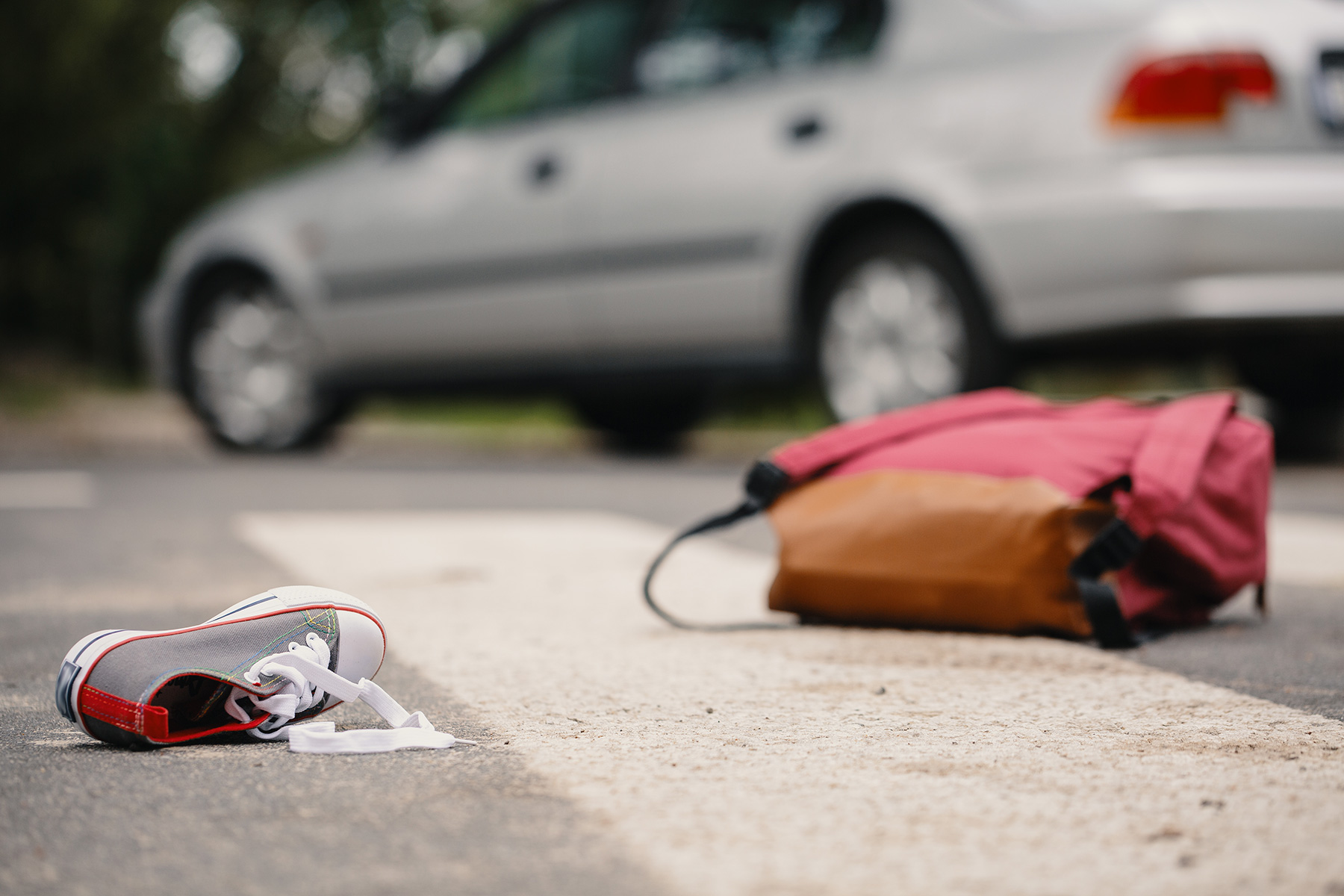 A child's backpack and shoe remain in the street after a car accident