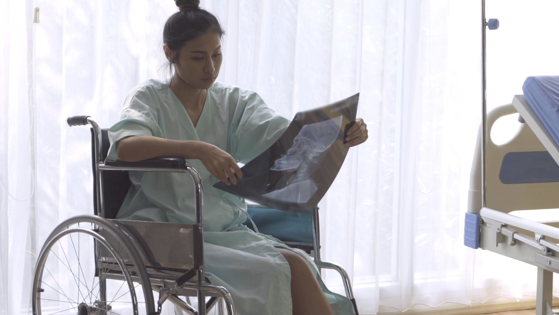 Woman sitting in a wheelchair examining X-rays after an accident
